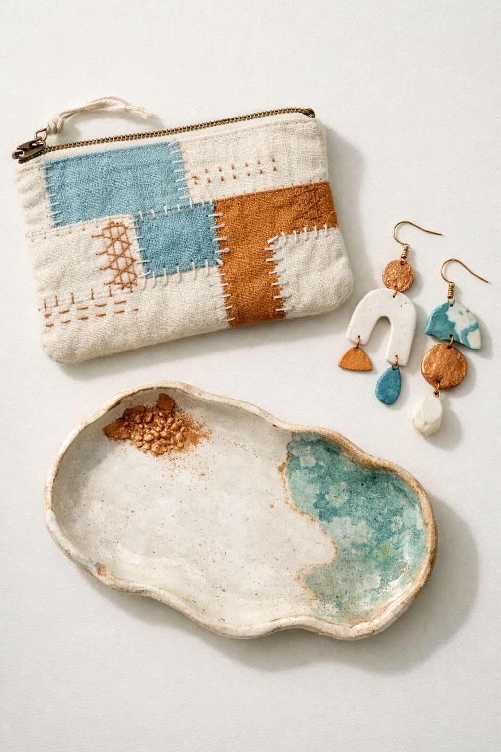 Imperfect by design 2026 trend mood board with mismatched handmade earrings, patchwork mended pouch, and organic pottery tray in patina blue and copper.