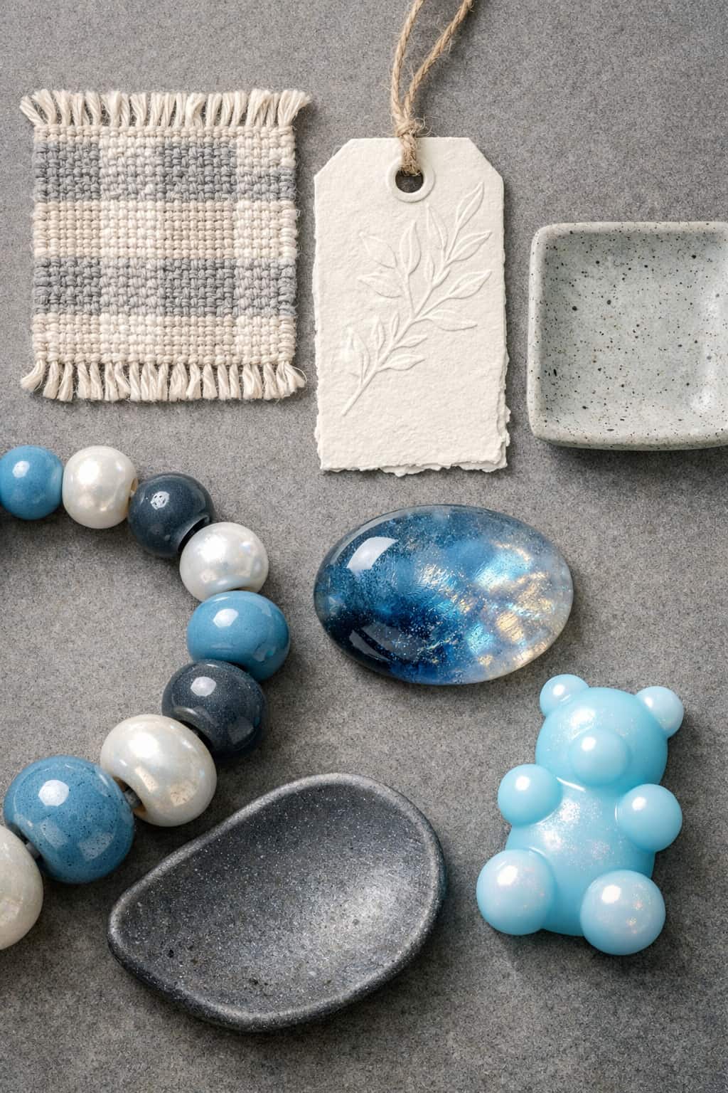 2026 texture trend collage with handmade linen coaster, embossed paper tag, speckled ceramic dish, glazed beads, resin cabochon, and gummy polymer clay charm.