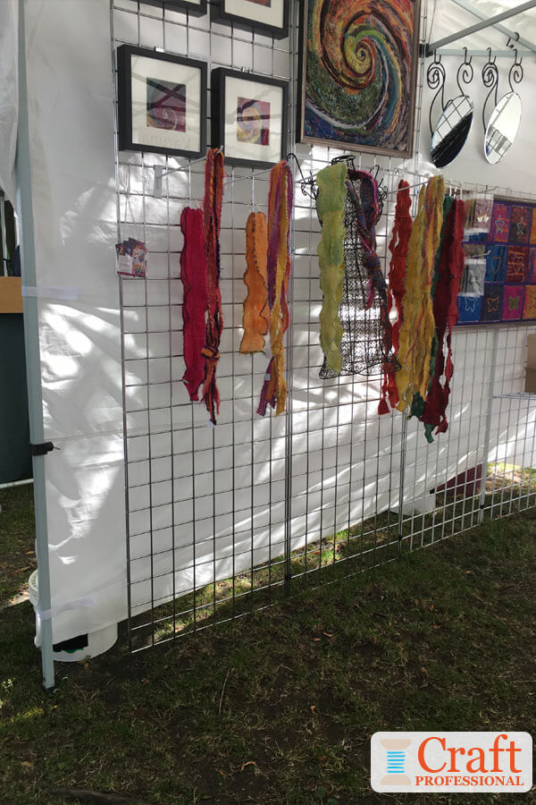 Colorful scarves and art displayed together in a craft tent at an outdoor show. Colorful scarves and art displayed together in a craft tent at an outdoor show.