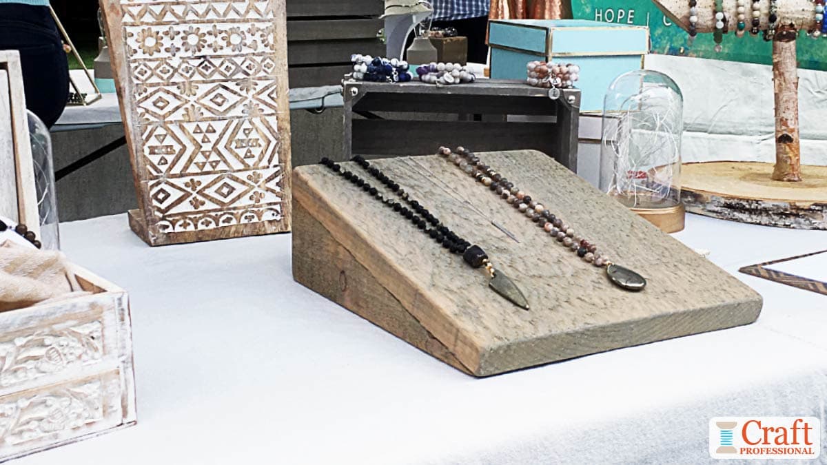 Handmade necklaces displayed on an angled tray at a craft show.