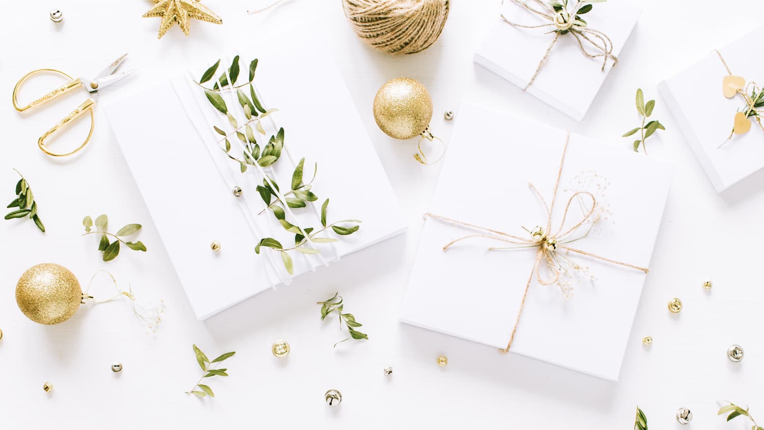 Christmas gifts wrapped in white with gold ribbon and greenery Christmas gifts wrapped in white with gold ribbon and greenery