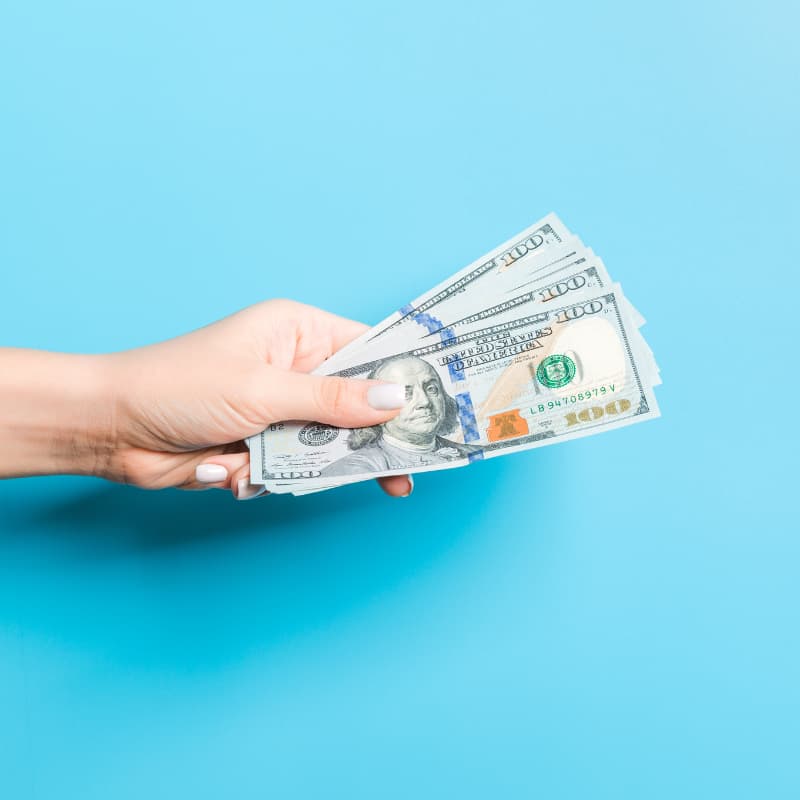 Hand holding dollar bills on blue background Hand holding dollar bills on blue background