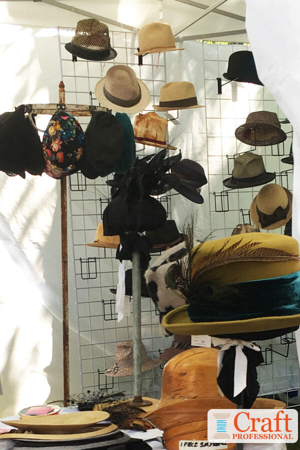 Eye catching green handmade hat adorned with a blue peacock feather displayed at the front of a craft booth grabs the attention of passing shoppers. Eye catching green handmade hat adorned with a blue peacock feather displayed at the front of a craft booth.