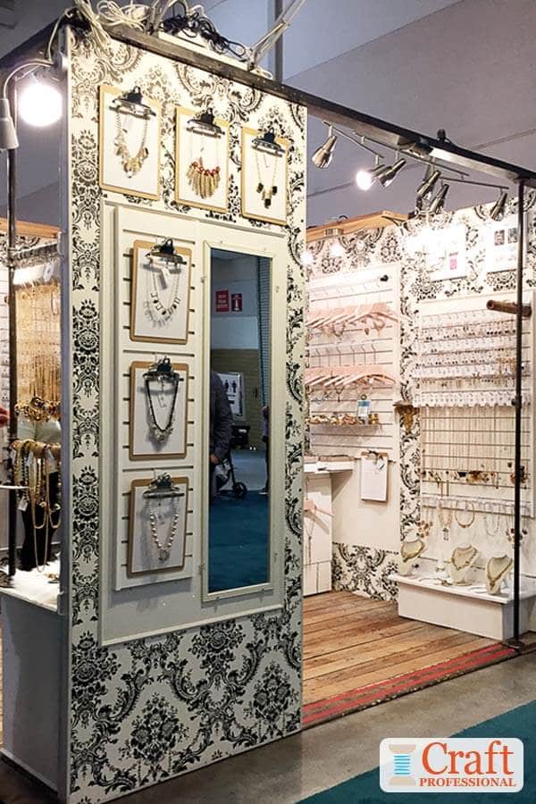 Handmade jewelry displayed on clipboards secured to a wall at a craft show demonstrate the impact of displaying items in odd numbered groups.