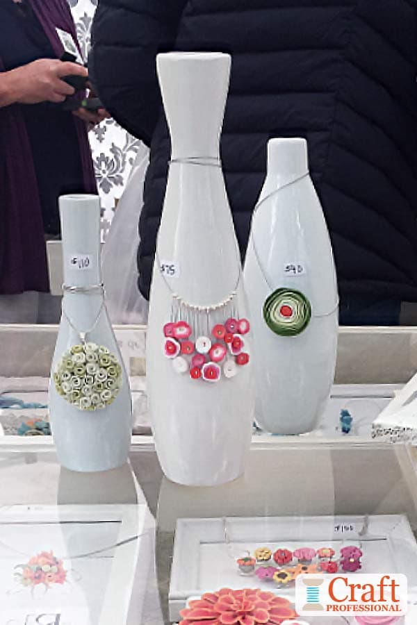 Pendants displayed on white vases.
