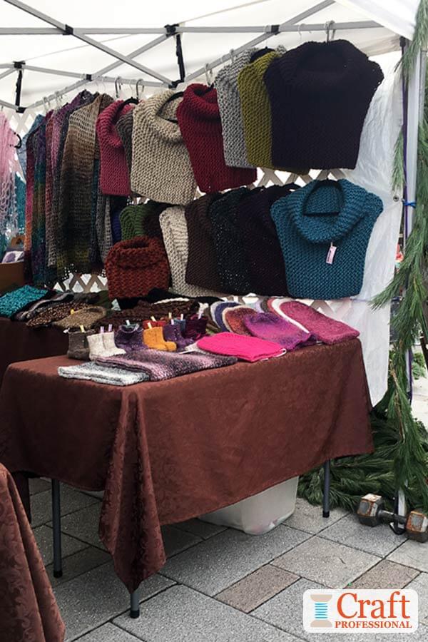 Hand knit accessories displayed in a craft tent at an outdoor farmers market. Hand knit accessories displayed in a craft tent at an outdoor farmers market.