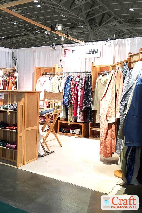 Handmade clothing on wood display racks at a craft show