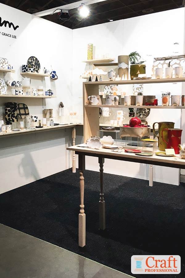 Pottery displayed at a craft show with neutral colored backdrop.