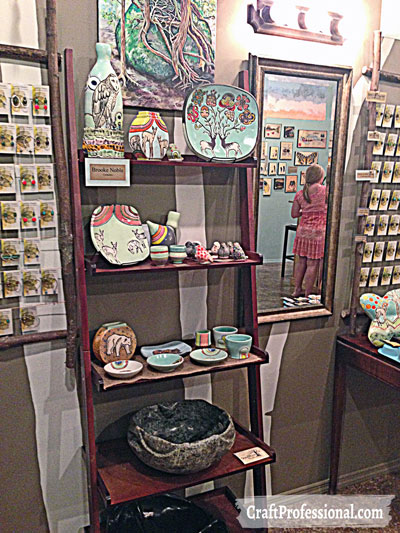 Handmade pottery displayed on a ladder shelf in a retail shop.