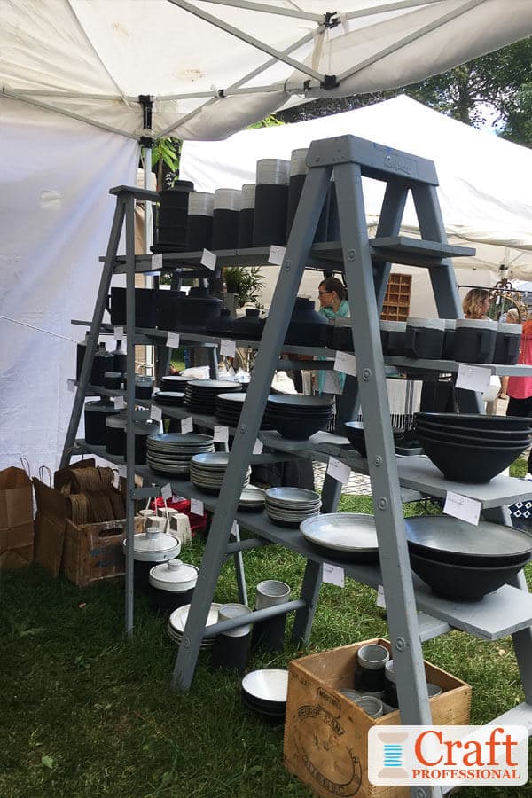 Craft show display featuring handmade pottery on portable shelves