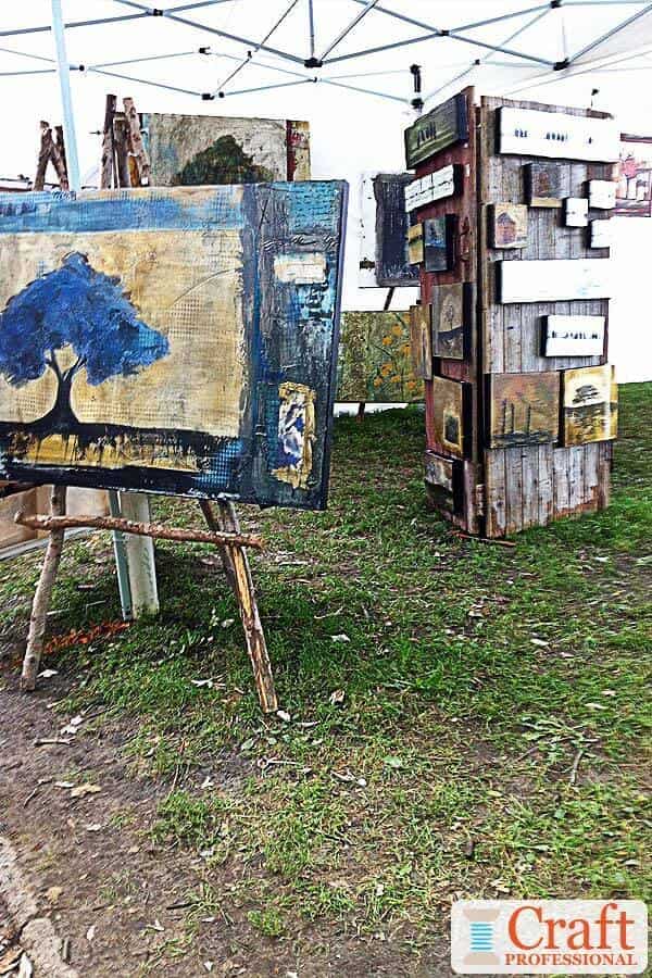 Paintings displayed at an outdoor craft show on DIY wood easels. Paintings displayed at an outdoor craft show on DIY wood easels.